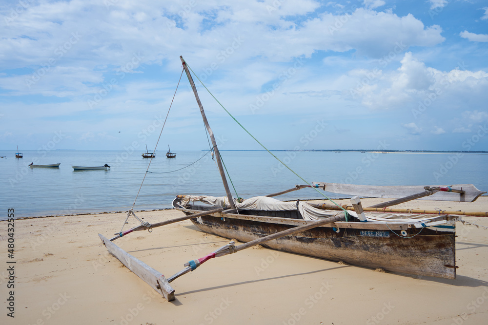 An old handmade African dhow fishing wooden boat on the beach. Outrigger canoe, traditional Vezo fishing boat                     