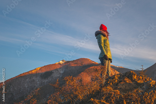 A young Caucasian redhead woman standing in the French Alps mountains in winter at sunset