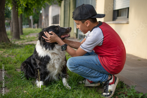 Boy about 10 years old looking at each other with his dog on the sidewalk of his house. And playing and hugging.