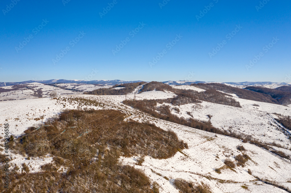 High voltage power lines in the mountains in winter aerial view