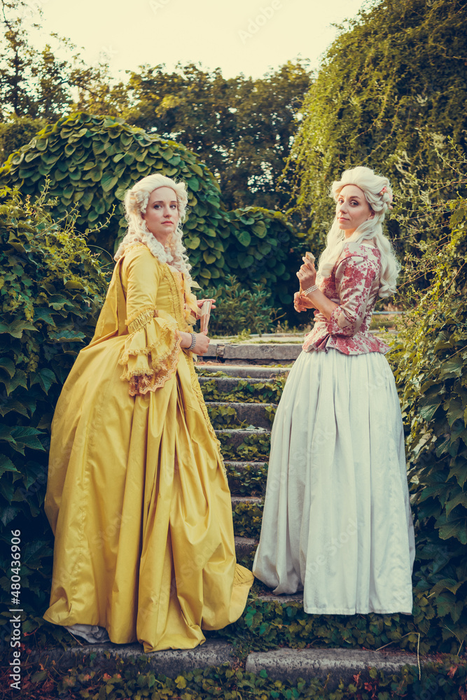 Portrait of two blonde woman dressed in historical Baroque clothes with old  fashion hairstyle, outdoors. Luxurious medieval dress Stock Photo