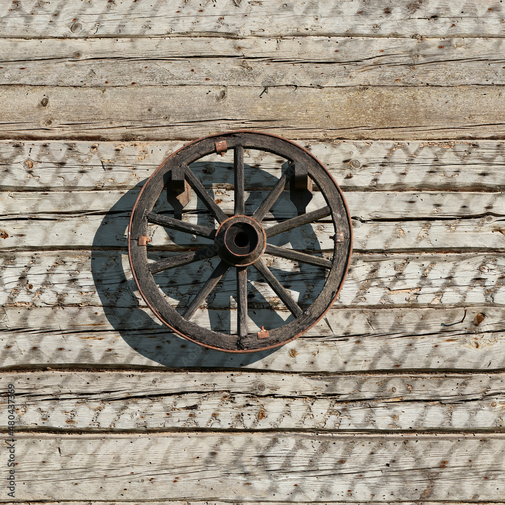 Seamless texture of the wall of an old village house from wooden logs with vintage wooden wheel. Belie Luga. Tinevichi. Belarus.
