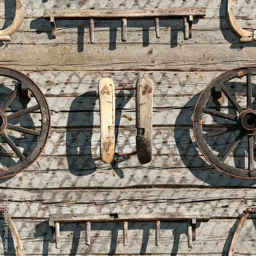 Seamless texture of the wall of an old village house from wooden logs with vintage wooden yoke, wheel, saddle tree and rakes. Belie Luga. Tinevichi. Belarus. photo