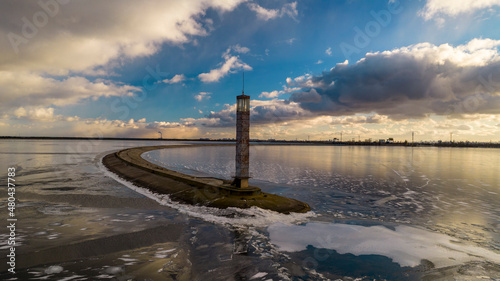 Aerial view of a pier with a lighthouse on a frozen lake