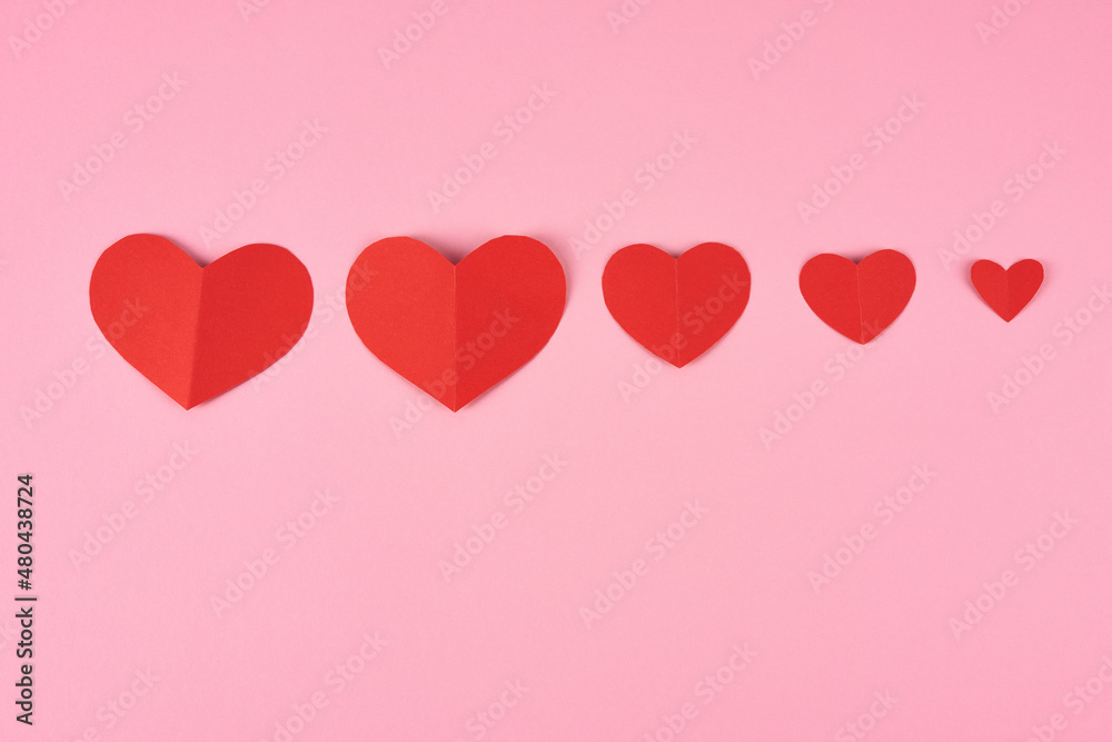 Red valentine greeting card in ascending order on a pink background.