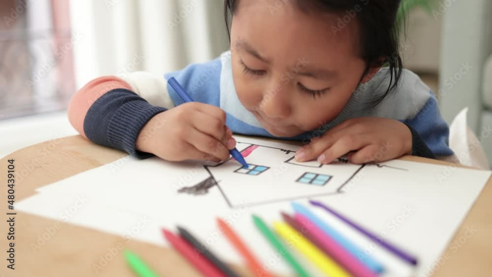 Asian young child boy drawing with crayons indoor at home Asian young child boy drawing with crayons indoor at home