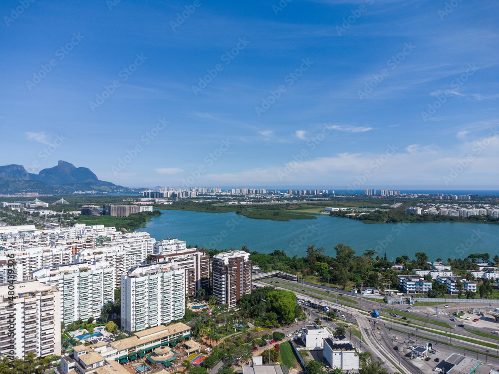 Aerial view of Jacarépagua lagoon in Rio de Janeiro, Brazil. Residential buildings and mountains around the lake. Barra da Tijuca beach in the background. Sunny day. Drone photo