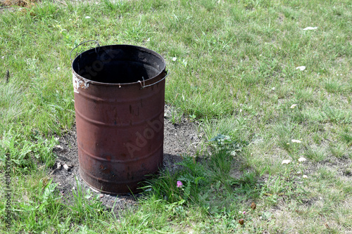 Burnt trash can on the grass in summer