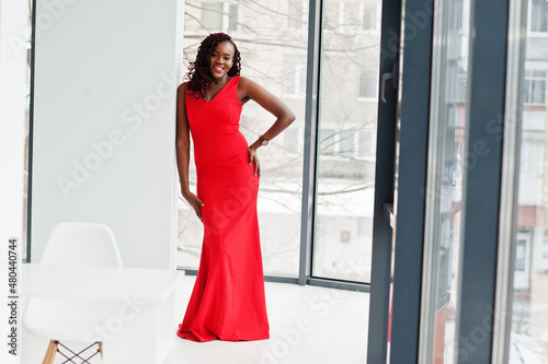 Magnificent young african woman in luxurious red dress in a luxury apartment. Beauty, fashion.