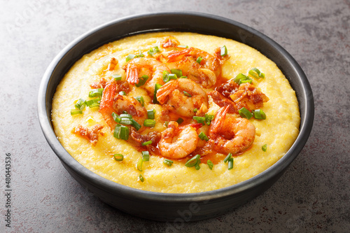 Delicious yellow grits with cheese, shrimps and bacon close-up in a plate on the table. horizontal