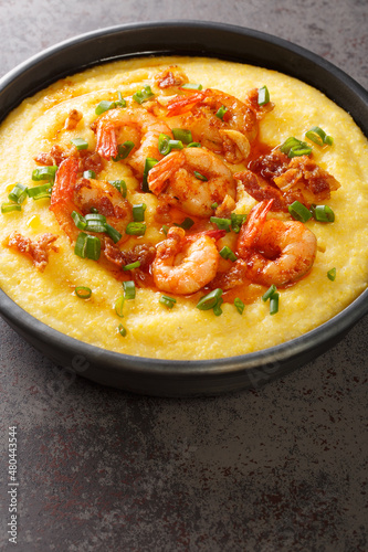 delicious fresh homemade cajun style shrimp and grits with cheddar closeup in the plate on the concrete table. Vertical