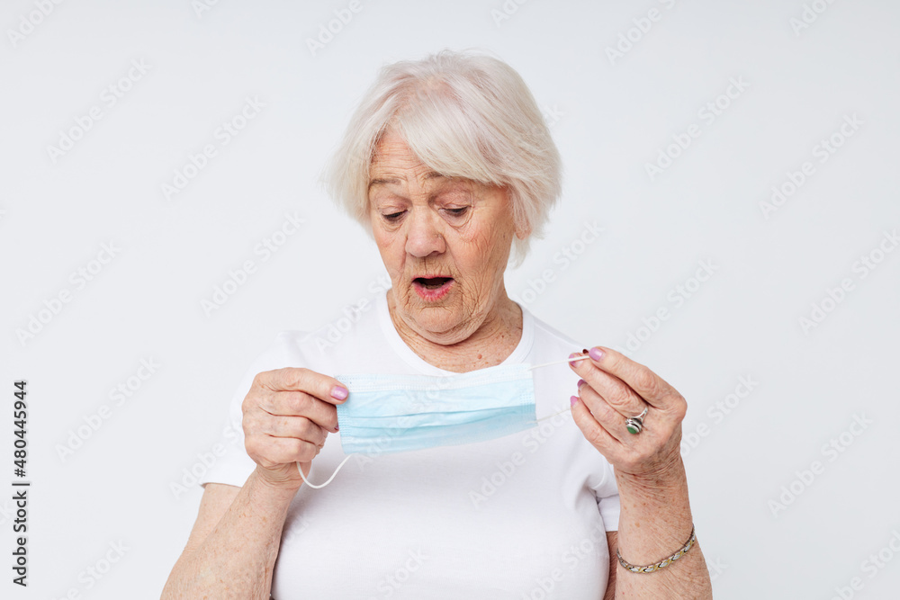 Portrait of an old friendly woman in casual t-shirt and medical mask close-up Portrait of an old friendly woman in casual t-shirt and medical mask close-up