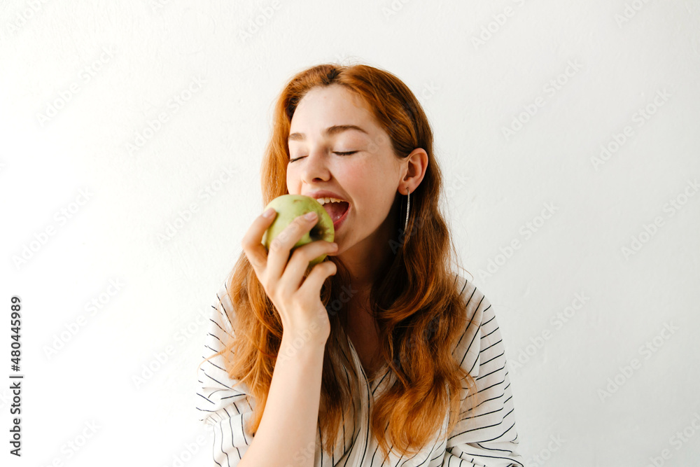 Close up portrait of beautiful young woman biting a green apple, having a snack after studying. Vegetarian food concept Close up portrait of beautiful young woman biting a green apple, having a snack after studying. Vegetarian food concept
