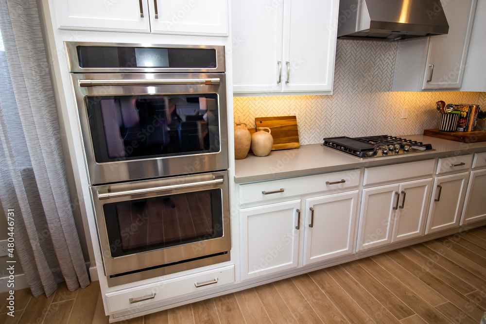 Fototapeta premium Kitchen With Stainless Steel Ovens & Range Hood, Gas Stove Top And Counter Decor