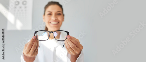 Doctor giving you new prescription glasses. Happy optometrist showing modern good quality eyeglasses. Optometry, eyewear, eye health concept. Grey text copyspace banner background, closeup, close up photo