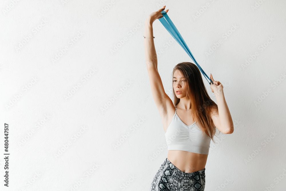 Athletic woman training with resistance bands in her hands above her head on white background Athletic woman training with resistance bands in her hands above her head on white background