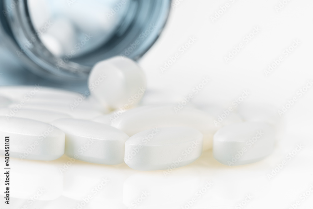 Pills and tablets spilling out of a plastic medical bottle, macro view Pills and tablets spilling out of a plastic medical bottle, macro view