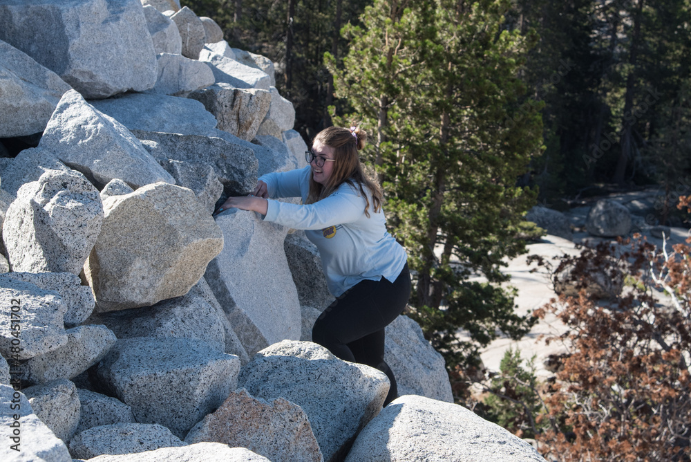 Beautiful Adventurous Woman Climbing Mountain Cliffside and Overlooking a Valley in Yosemite National Park