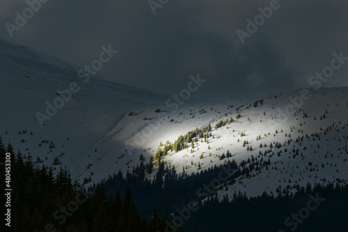 A ray of sunshine that illuminates just a spot on the mountain peak - snow mountain landscape