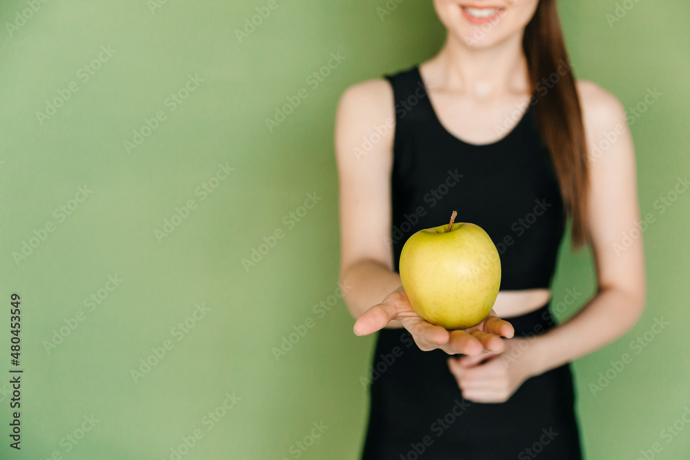 Selective focus, young woman holding a green apple isolated over green background. Eating vitamins Selective focus, young woman holding a green apple isolated over green background. Eating vitamins