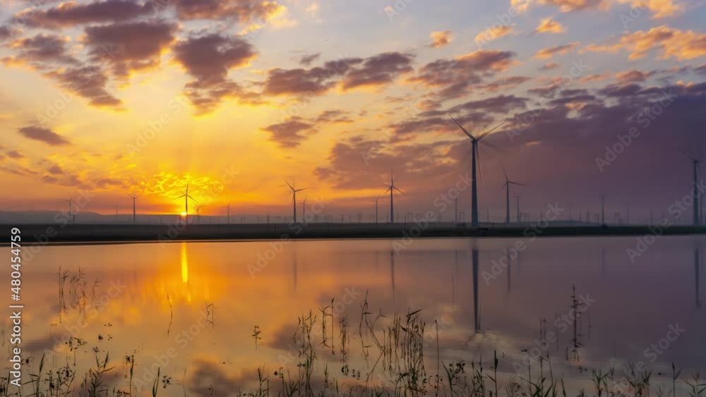 Windmills windpower turbines near lake with sunrise sun reflection in water landscape, timelapse 4k Windmills windpower turbines near lake with sunrise sun reflection in water landscape, timelapse 4k