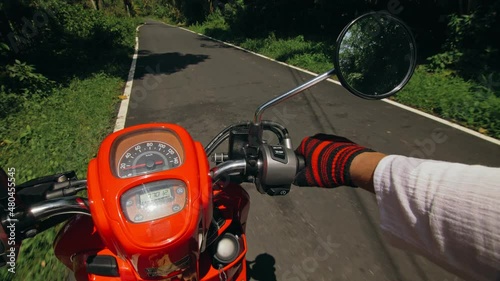 Scooter road trip. POV view, first person. Men on red motorbike in white clothes on drive forest road trail. Hold the steering wheel motorbike. photo