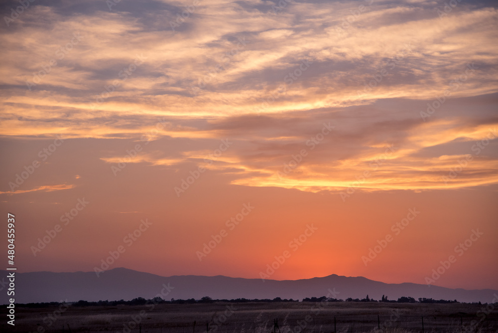 Mountain Sunset with Silhouetted Windmill and Clouds in a Colorful Sky