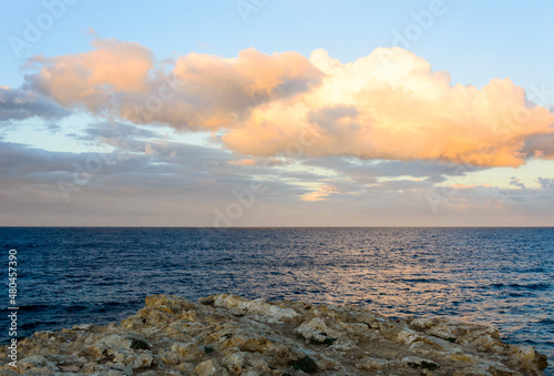 Whie purple and orange sunset clouds above the dark blue sea and rocks on the shore in Tunisia  Africa