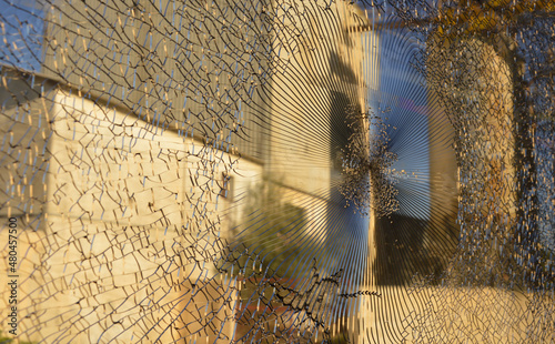 Defocused view of an industrial structure in Tunisia, Africa, through a broken glass of the train window. Blurred white, yellow and brown factory walls and radial cracks on the glass.