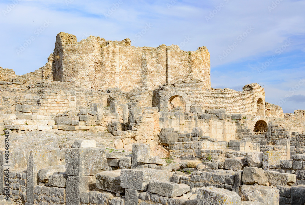Ruins of the antique Roman city of Thugga in Tunisia, Africa.  Blue sky with clouds, old yellow stone walls