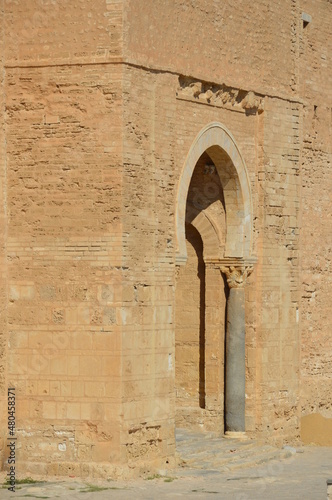 Ancient arabic ribat fortress doorway in Monastir, Tunisia, Africa. Old Roman columns with capitels, yellow stones, sunlight and shadows on the ancient walls photo