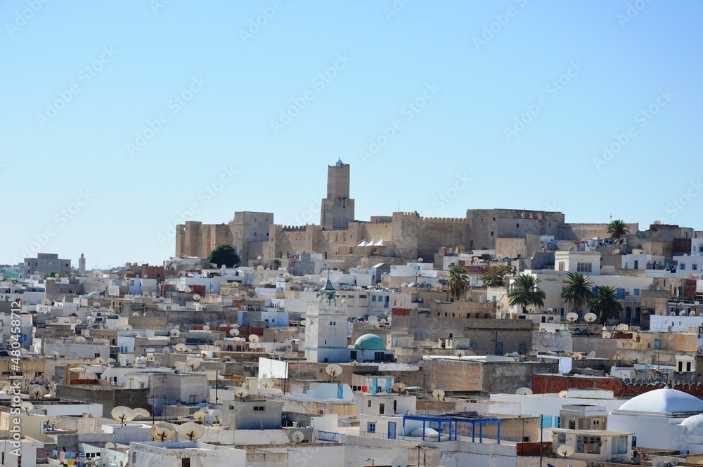 View of the ancient arabic Kasbah fortress, lighthouse and old town of Sousse, Tunisia, Africa. Sunlight and shadows on the ancient walls, blue sky