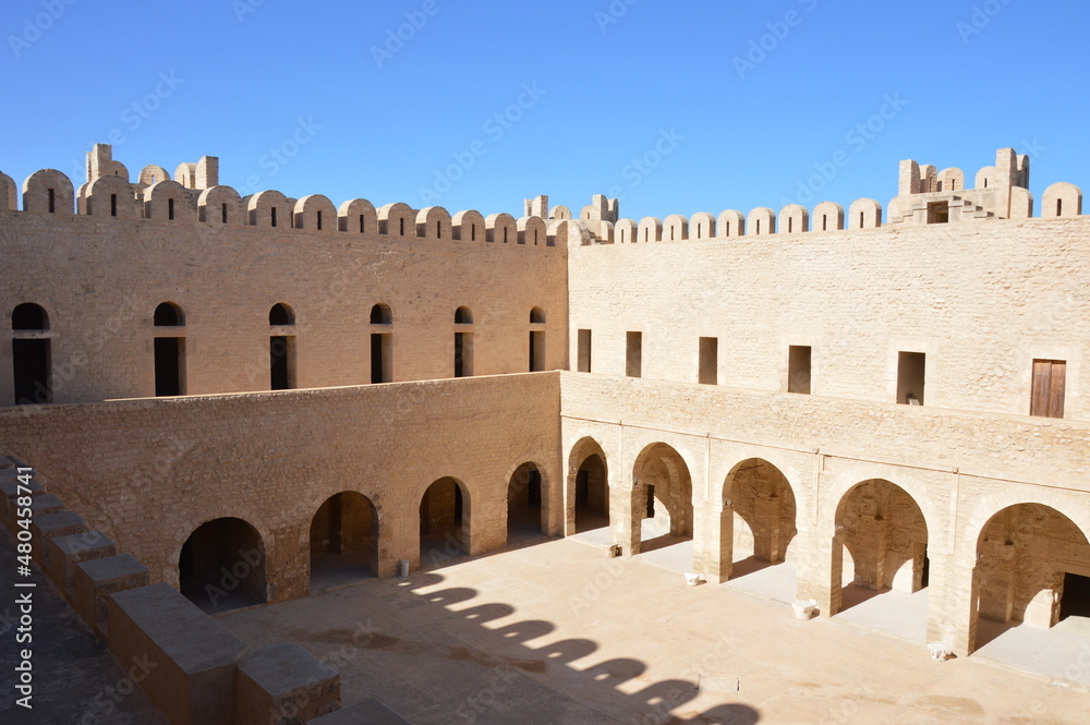 The inner yard of VIII century  arabic fortress (ribat) in Sousse, Tunisia, Africa. Blue sky, old arches, shadows and sunlight on the ancient stone walls