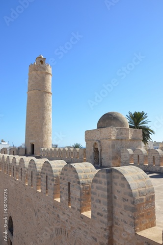 The tower and wall pathway of VIII century arabic fortress (ribat) in Sousse, Tunisia, Africa. Blue sky, old arches, shadows and sunlight on the ancient stone walls