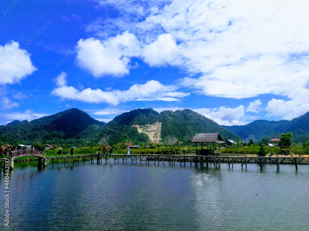 wooden bridge, outdoor natural landscape on the background with a clear blue sky in the middle of the lake