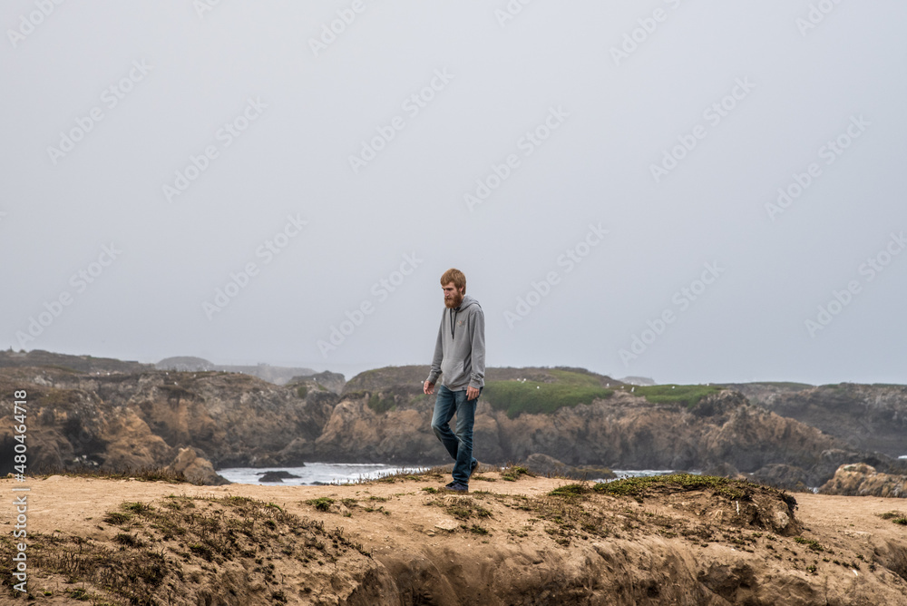 Man Hiking Through Tide Pools Along California Coast on a Cloudy Day at Fort Braggs
