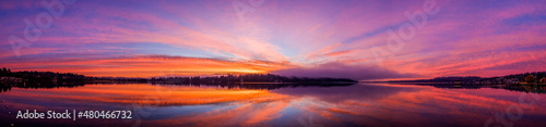 Sunrise over Lake Washington results in a colorful sky and reflection on the water, with foggy forest in the foreground © Harrison