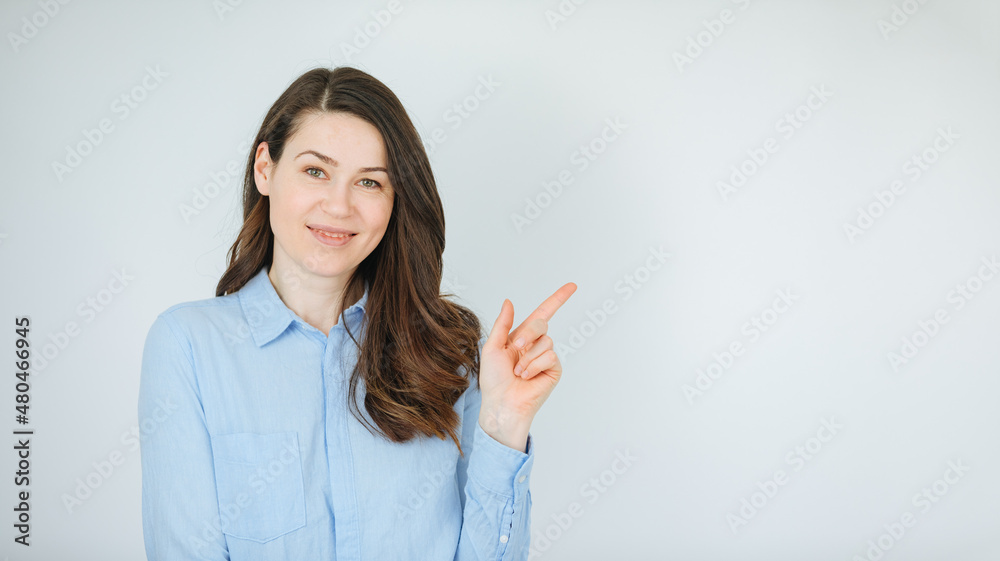 Woman wearing blue shirt pointing finger at something. Copy space. Job advertisement for young people. job announcement Woman wearing blue shirt pointing finger at something. Copy space. Job advertisement for young people. job announcement