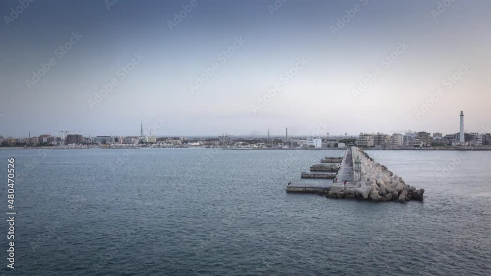 Cement blocks along pier at harbor with cityscape in background Cement blocks along pier at harbor with cityscape in background