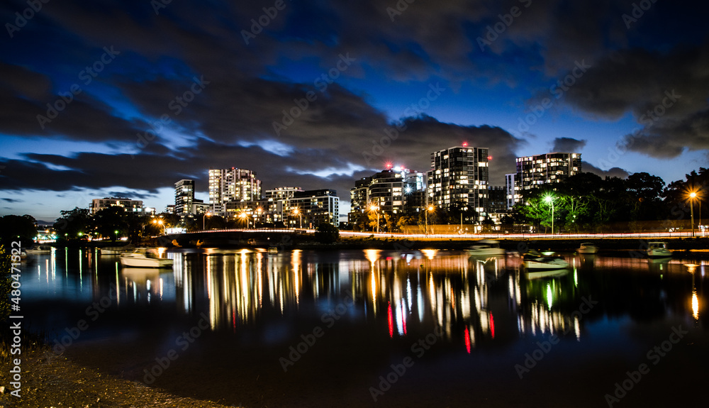 Cityscape night shows its shadow on water and clouds on the sky at the port in Cook river, Sydney, Australia.