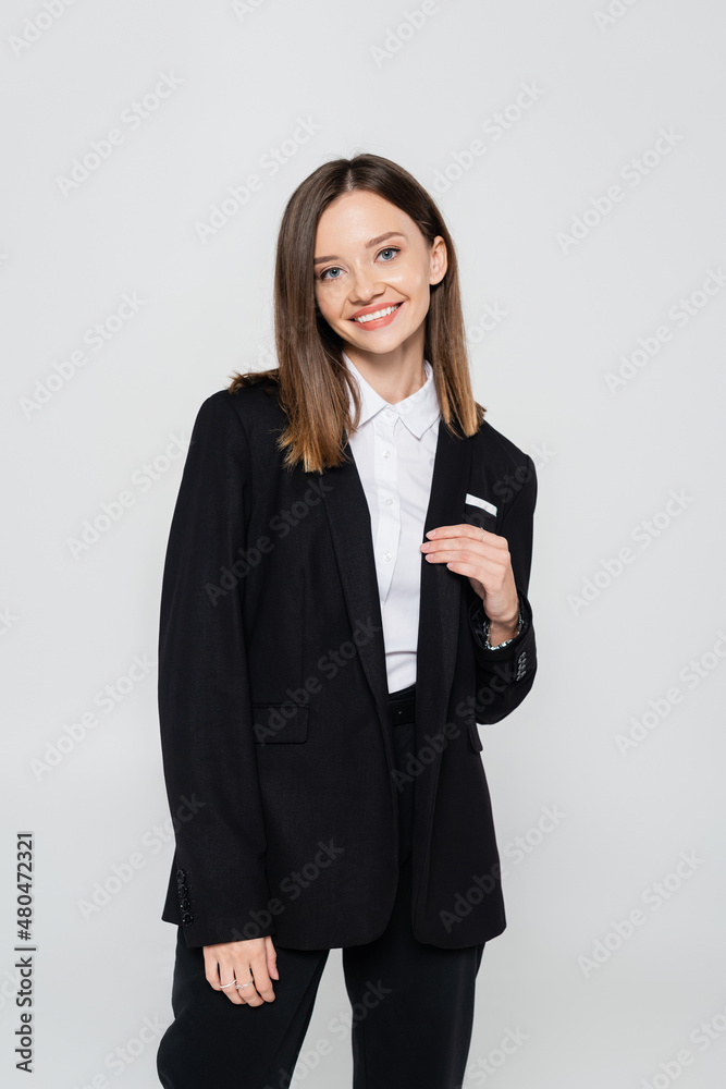 happy and stylish woman in suit smiling isolated on grey. happy and stylish woman in suit smiling isolated on grey.