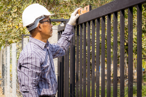 Close-up of half a technician installing a metal door on a very sunny day.