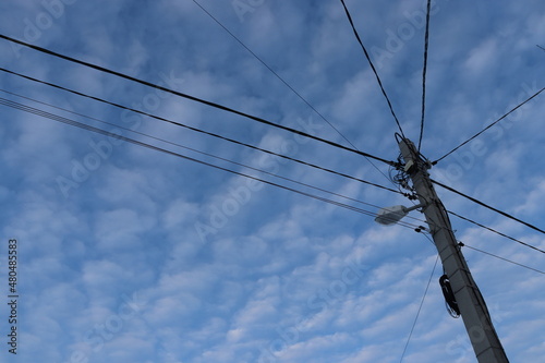 concrete pillar with lots of wires against the sky
