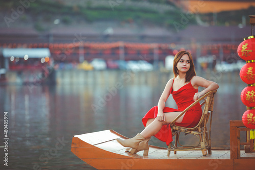 Beautiful Asian Chinese Woman Wearing Cheongsam Traditional Red Dress on Chinese New Year travel on vacation Posting on a boat in the river.