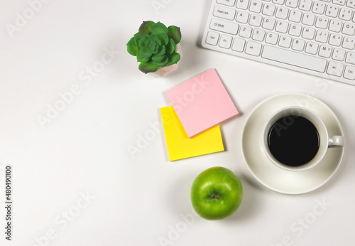 Green apple with a cup of black coffee,computer keyboard, succulent plant pot and sticky note paper. on pink background with copy space.  Healthy snack and lunch with working in office. photo