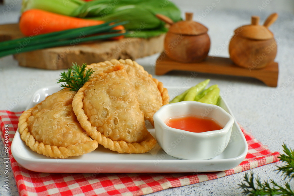 a plate of fried pastries containing vegetables served with sauce against white background