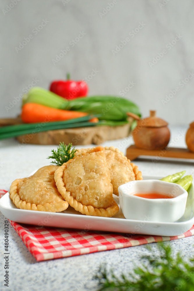 a plate of fried pastries containing vegetables served with sauce against white background a plate of fried pastries containing vegetables served with sauce against white background