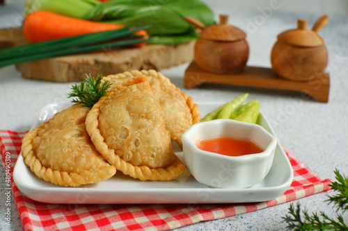 a plate of fried pastries containing vegetables served with sauce against white background