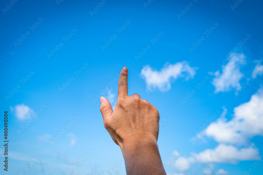 Man hand pointing at something or touching screen on blue sky with cloud background, closeup of hand Man hand pointing at something or touching screen on blue sky with cloud background, closeup of hand