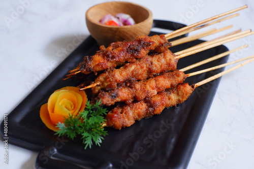 a plate of grilled chicken in bamboo skewer named satay against white background 